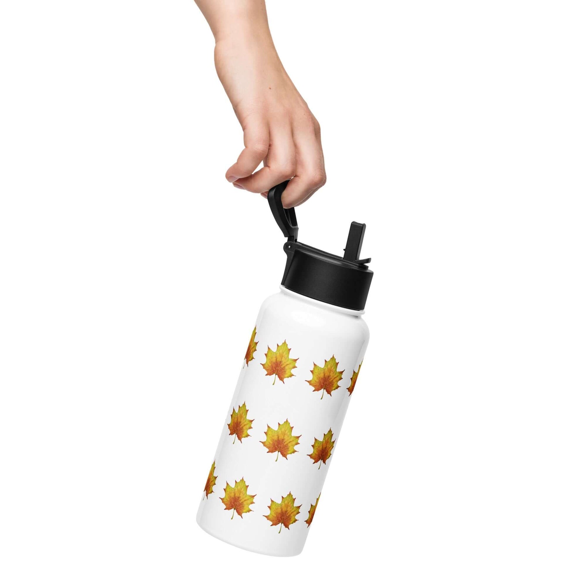 Hand holding a stainless steel water bottle featuring a rustic maple leaf design, ideal for hydration on the go.