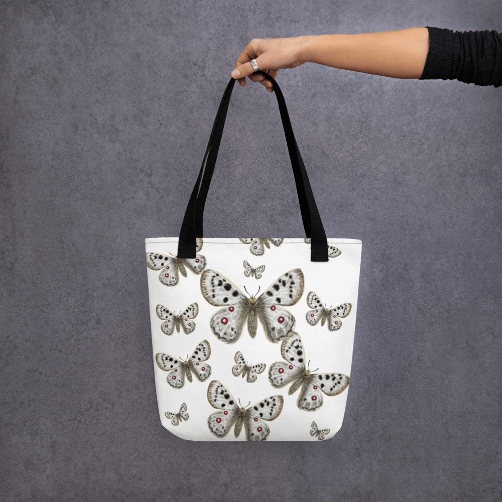 Apollo all-over print tote bag with black handles held by a hand holding it straight
