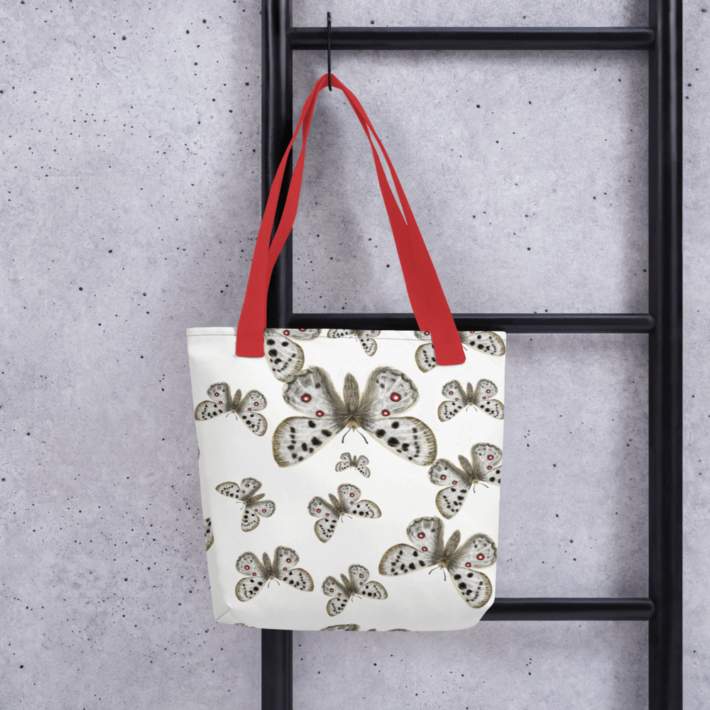 Apollo all-over print tote bag with red handles hanging on a ladder
