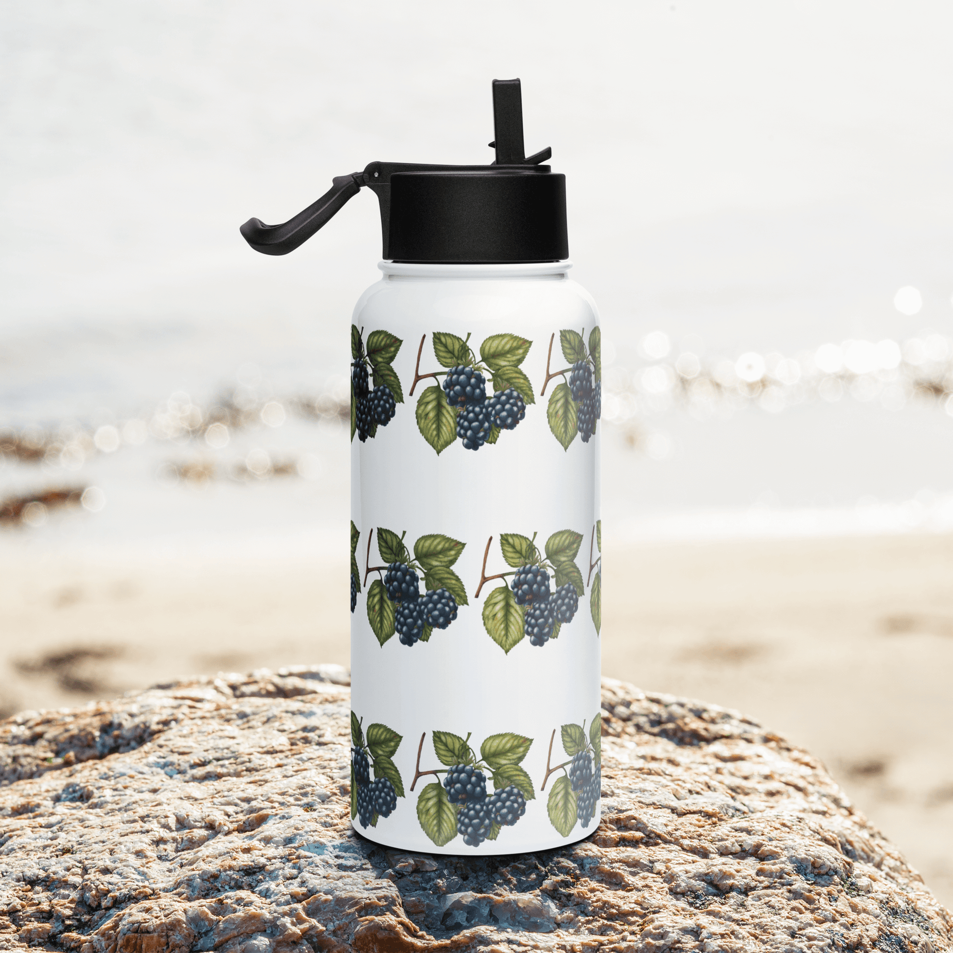 Deep purple blackberry stainless steel tumbler on a rocky beach, perfect nature-inspired gift for hydration.