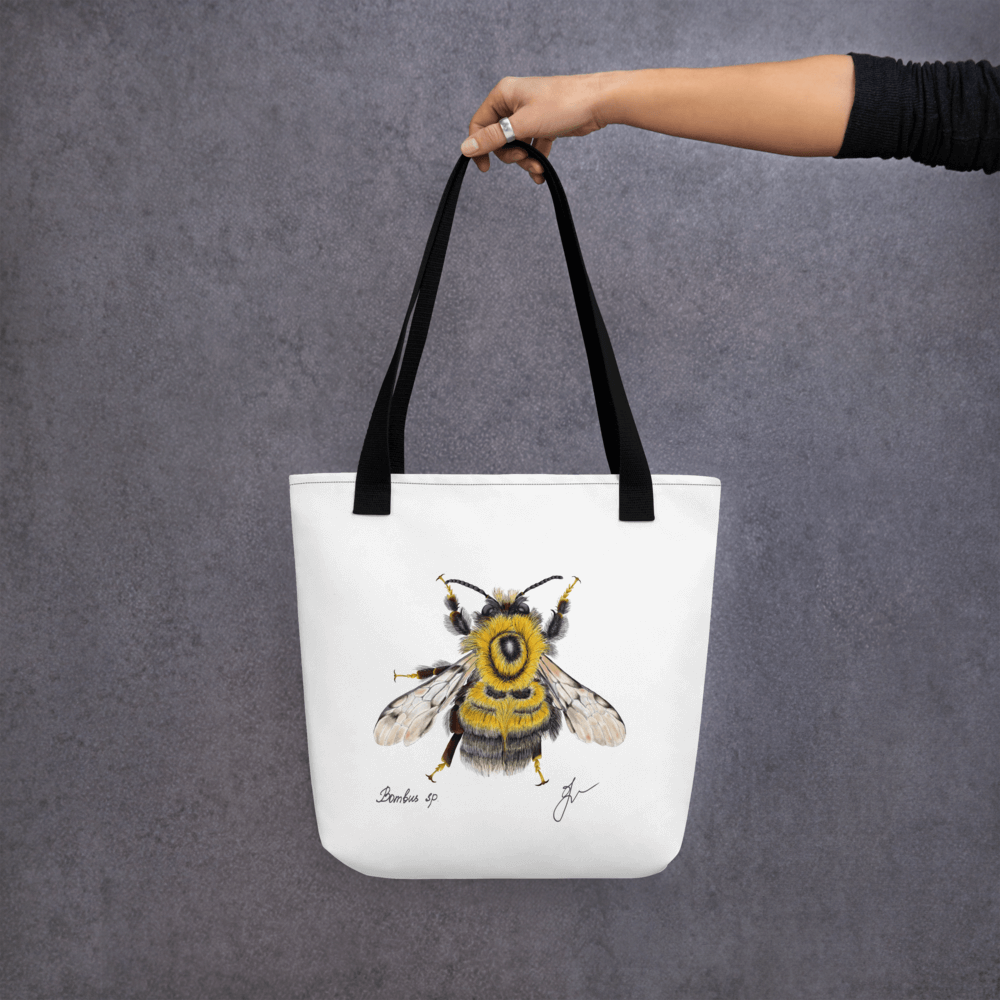 Bumblebee all-over print tote bag with black handles held by a hand holding it straight
