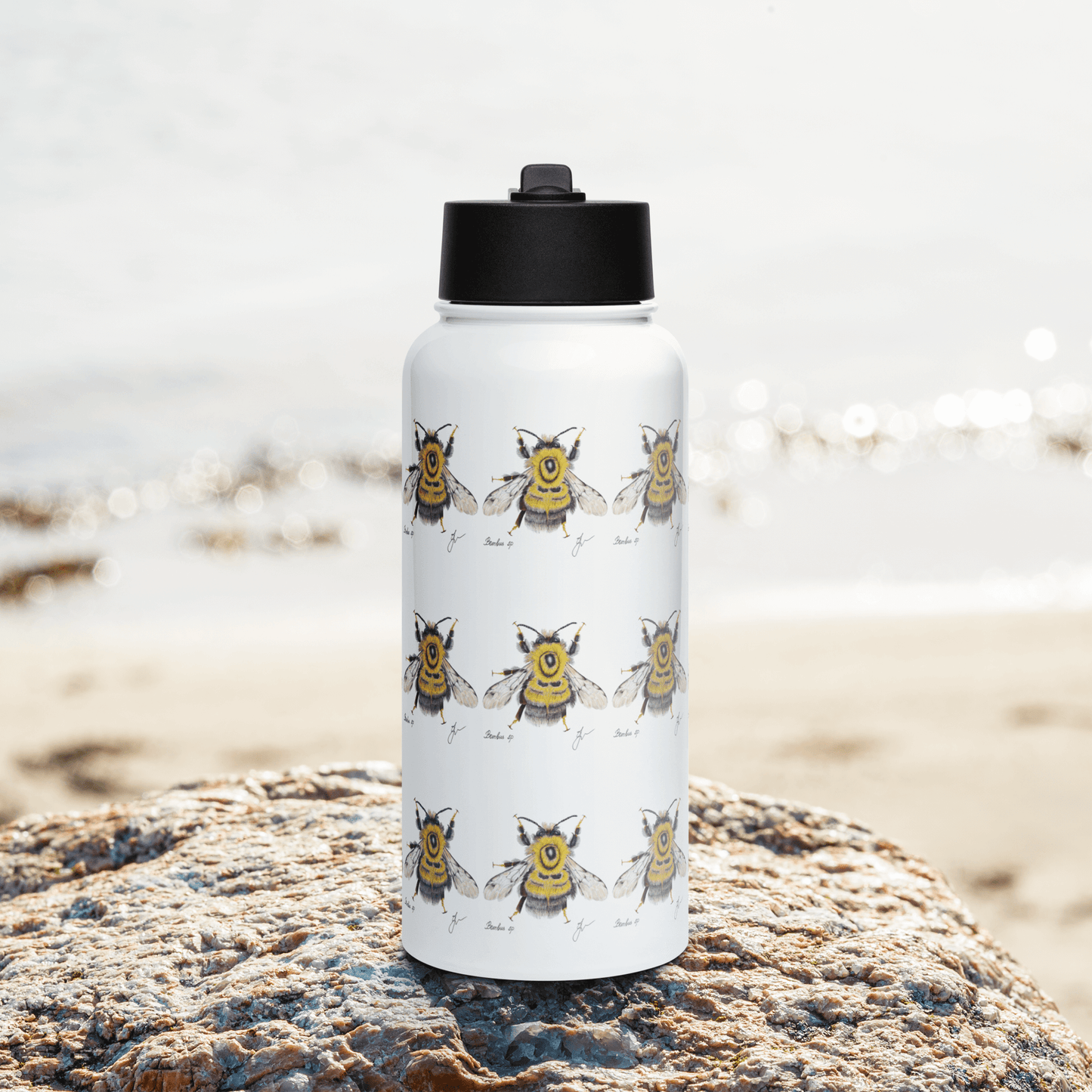 Charming Bumblebee water bottle on a rock by the beach, perfect for summer hydration and thoughtful gifting.