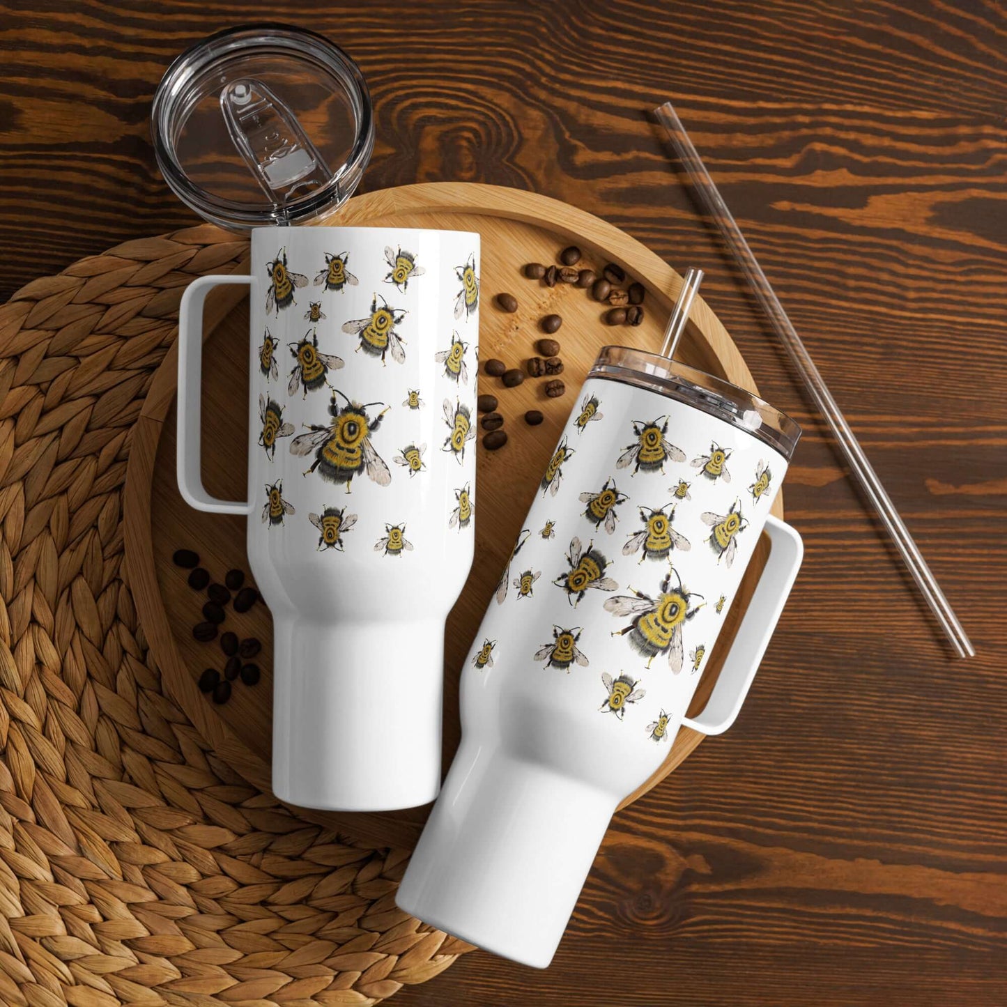 Bumblebee design insulated travel tumblers with handles, coffee tumbler on a wooden tray with coffee beans and straw.