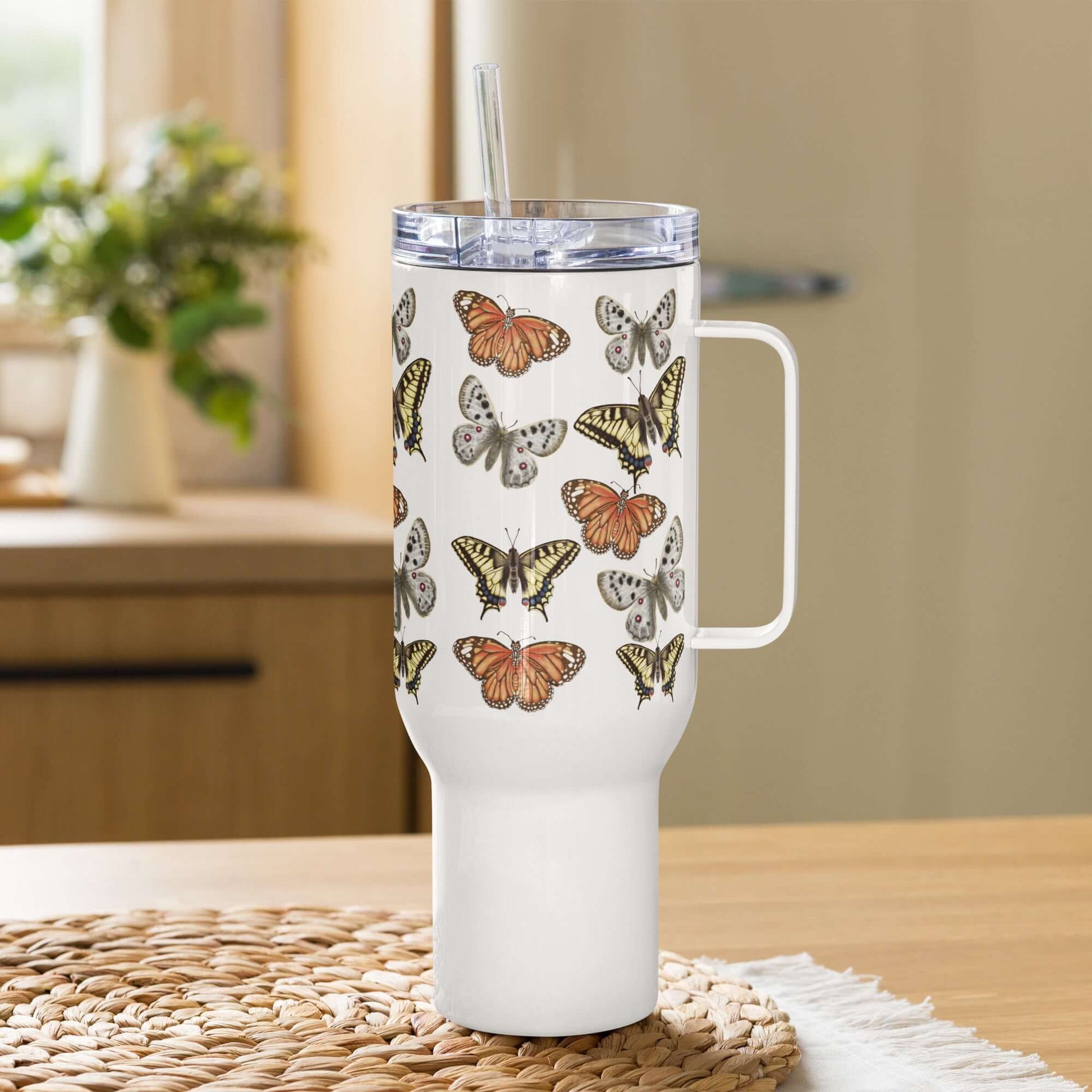 Stainless steel travel tumbler with butterfly designs, featuring a handle and straw, perfect for drinks on the go.