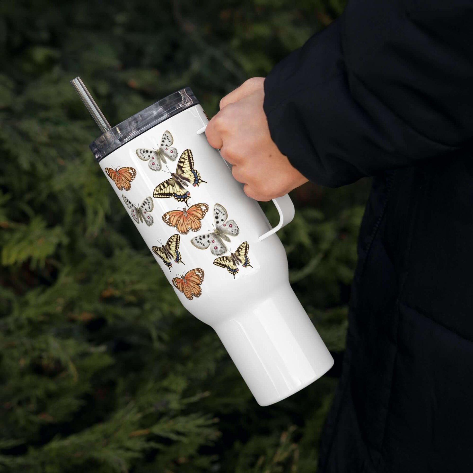 Hand holding a butterfly design stainless steel tumbler with straw, ideal for travel and drinks on-the-go.