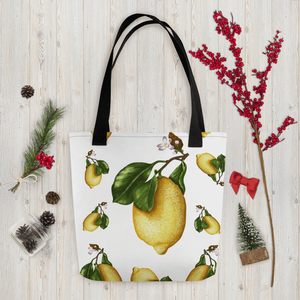 Lemon all-over print tote bag with black handles within Christmas decorations like red berry little branch
