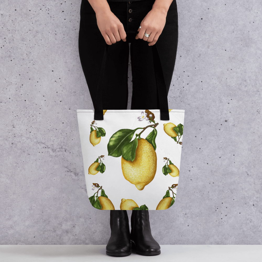 Lemon all-over print with black handles held by a person dressed in black with both hands holding it in front
