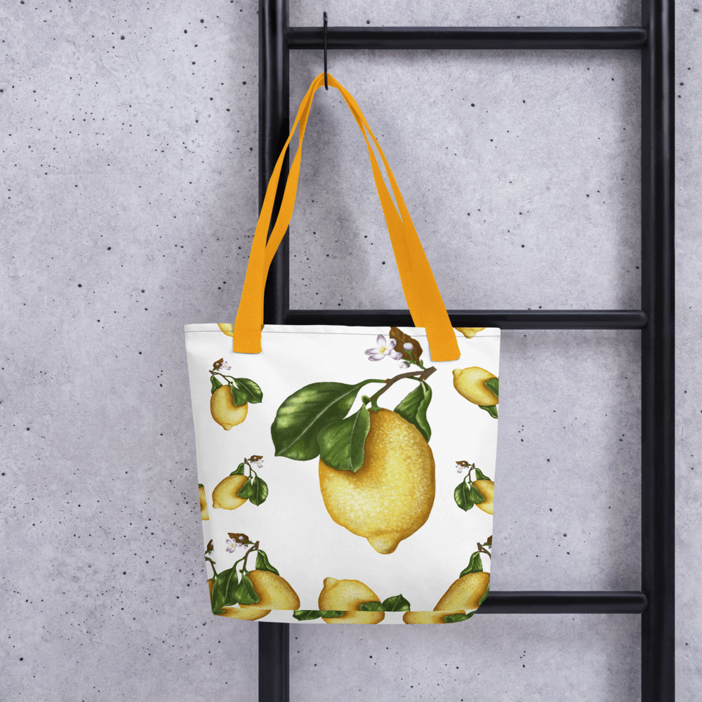 Lemon all-over print tote bag with yellow handles hanging on a ladder
