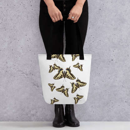 Machaon all-over print with black handles held by a person dressed in black with both hands holding it in front
