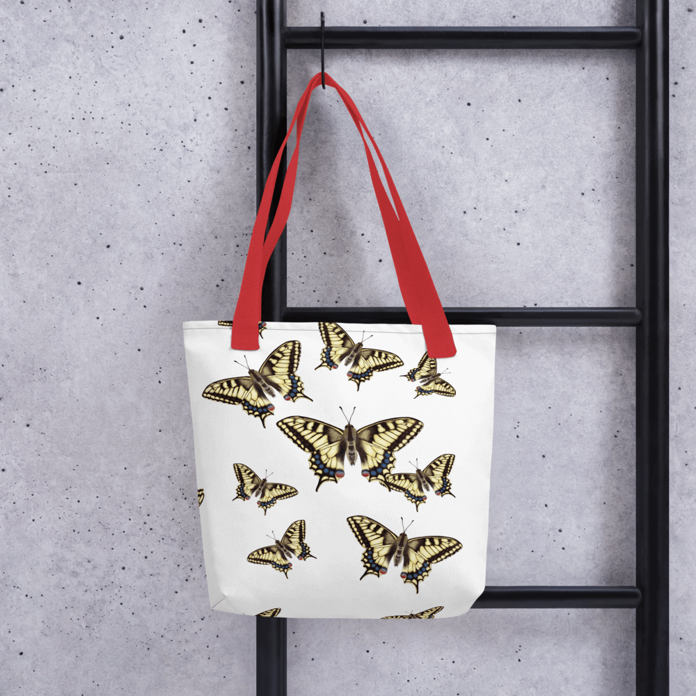 Machaon all-over print tote bag with red handles hanging on a ladder
