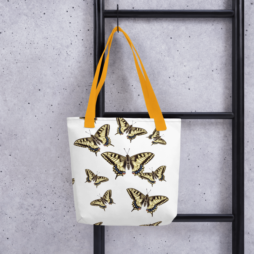 Machaon all-over print tote bag with yellow handles hanging on a ladder
