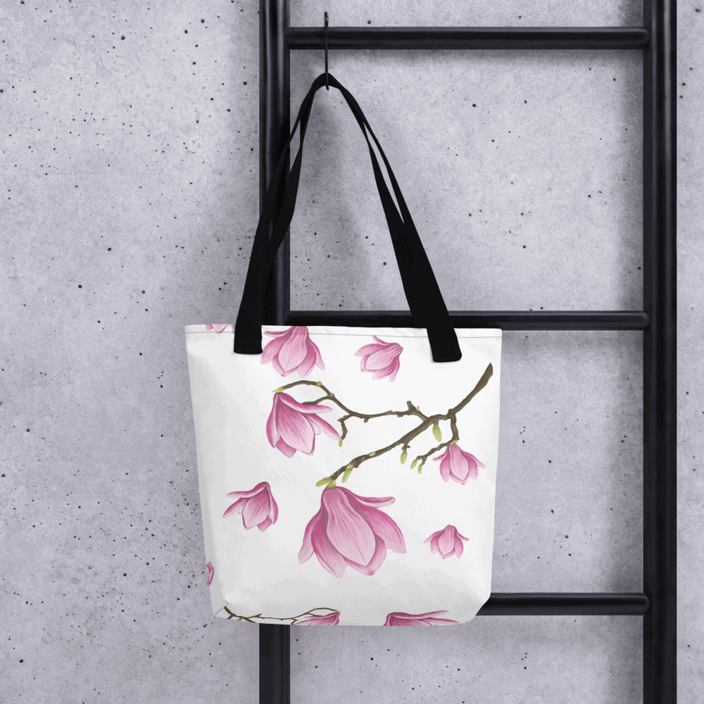 Magnolia all-over print tote bag with black handles hanging on a ladder from the other side