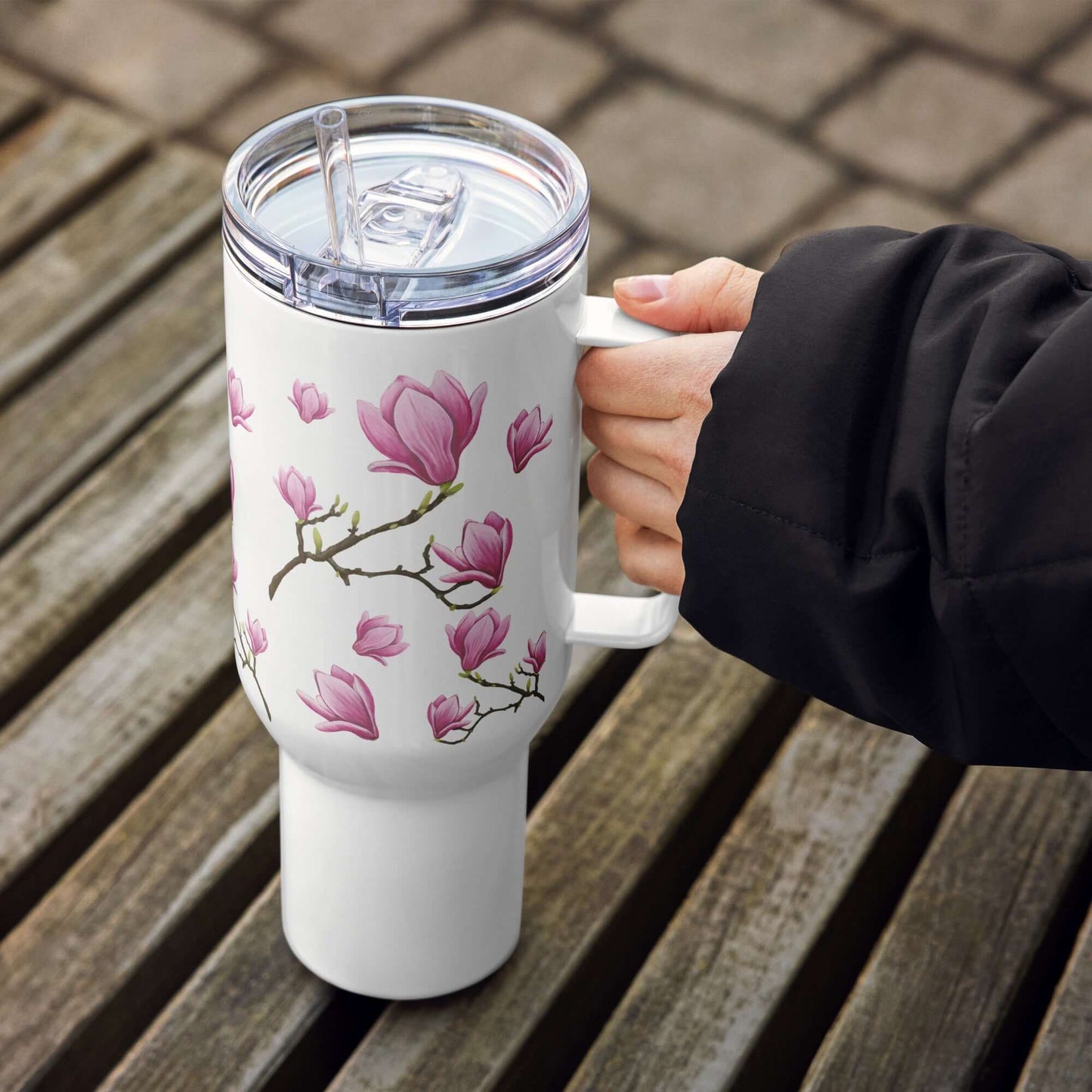 Magnolia Design Tumbler with handle, 25oz or 40oz, showcased on wooden surface, ideal for travel and outdoor hydration.