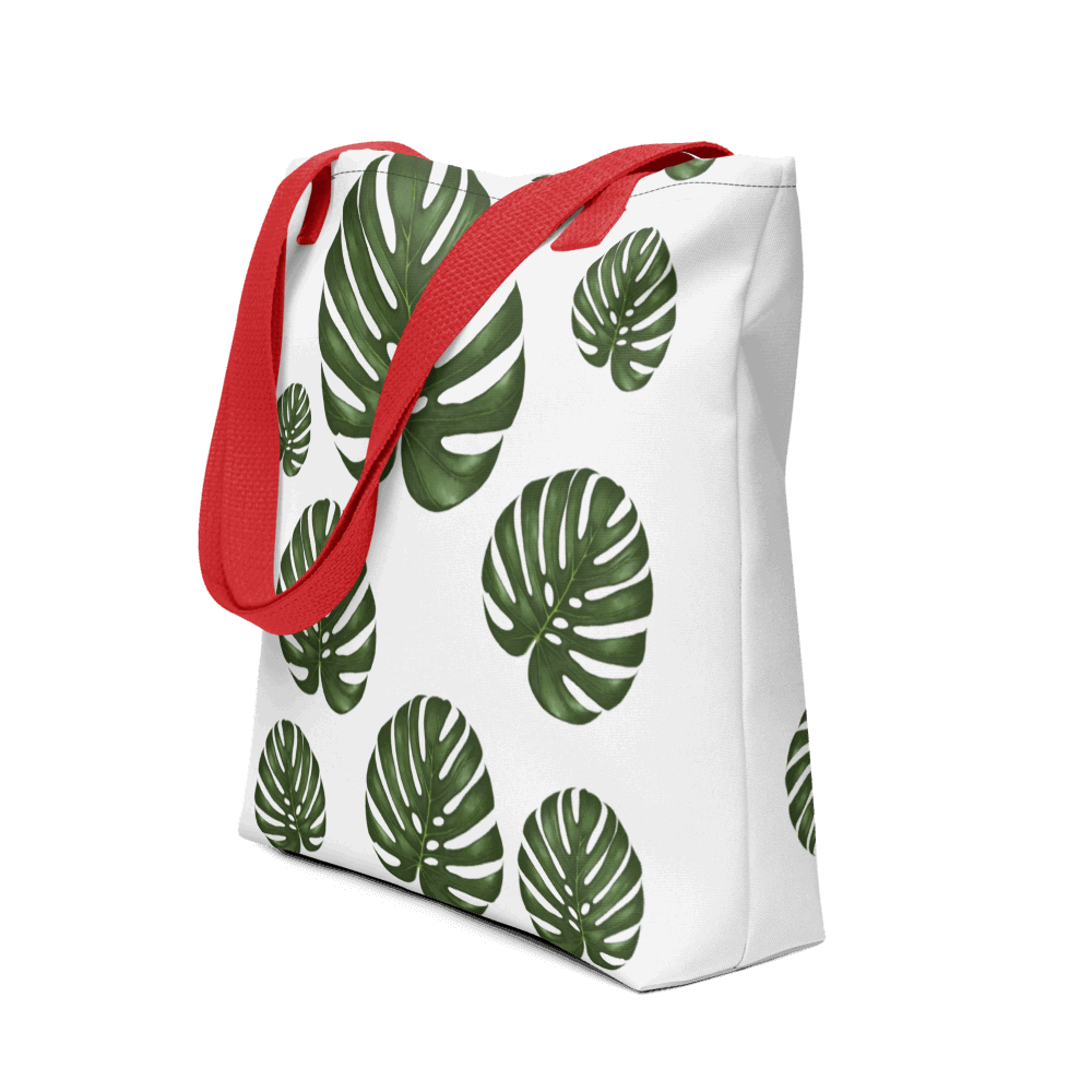 Monstera all-over print tote bag with red handles displayed prominently