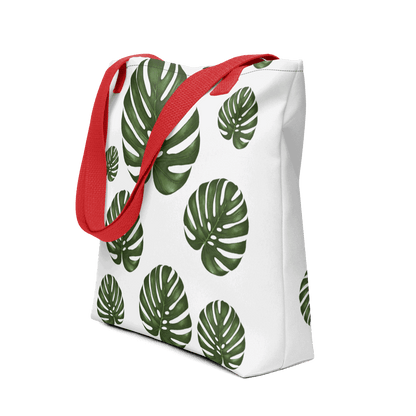 Monstera all-over print tote bag with red handles displayed prominently