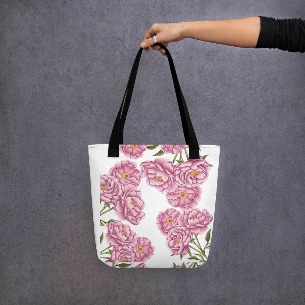 Peony all-over print tote bag with black handles held by a hand holding it straight