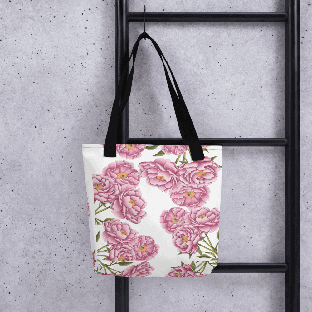 Peony all-over print tote bag with black handles hanging on a ladder