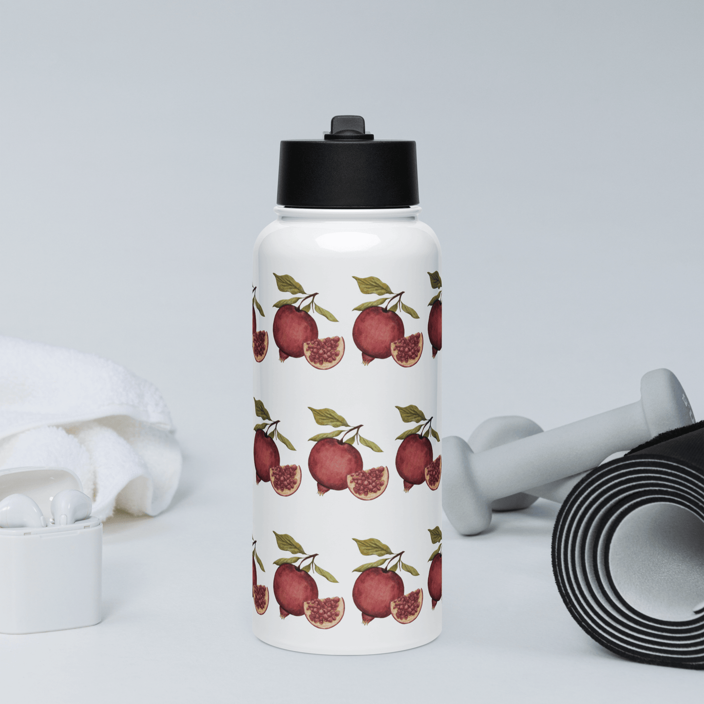 Stylish pomegranate-patterned stainless steel water bottle with fitness accessories in the background.