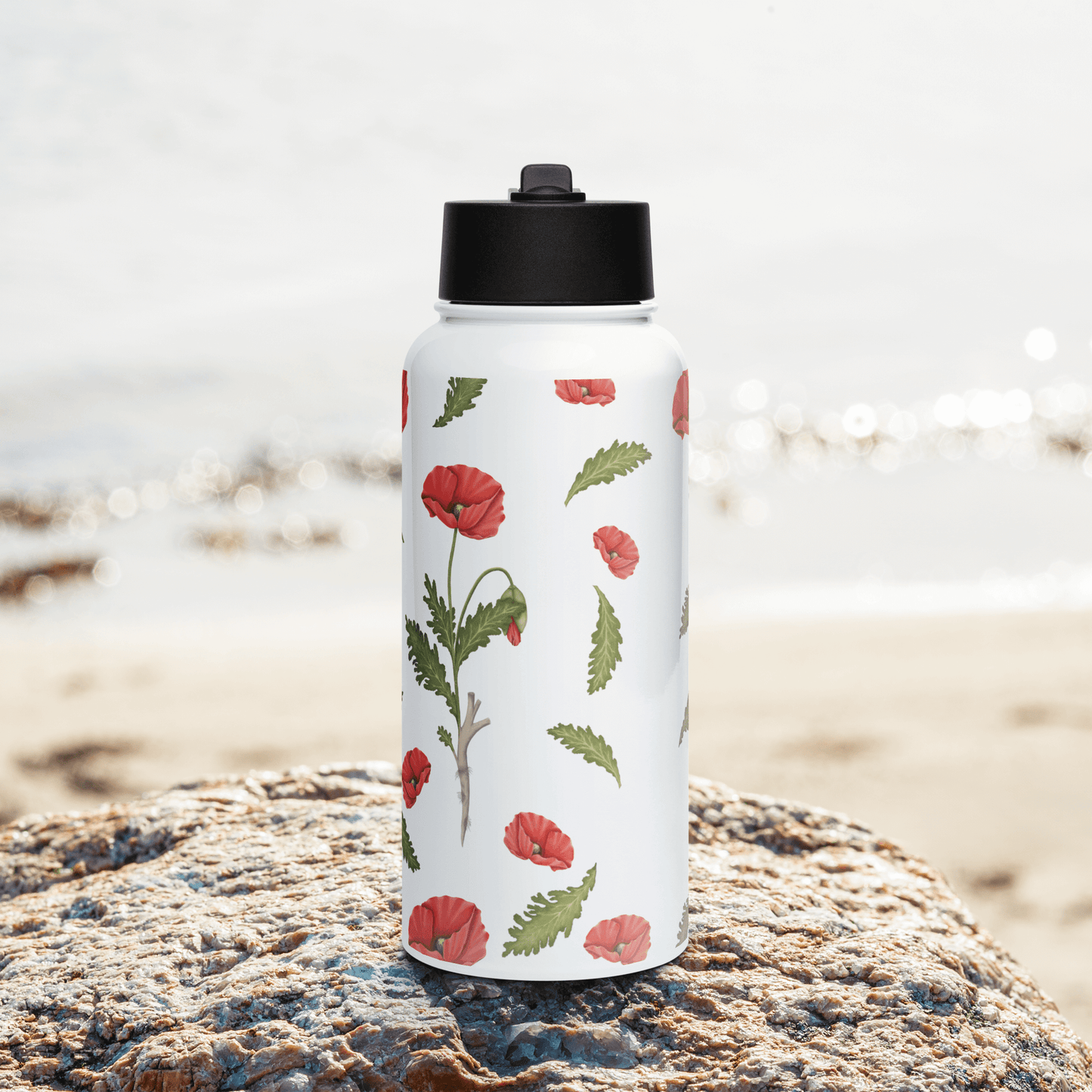 Personalized 32oz Poppy water bottle on a beach rock, showcasing vibrant floral design, perfect for unique gifts and hydration.