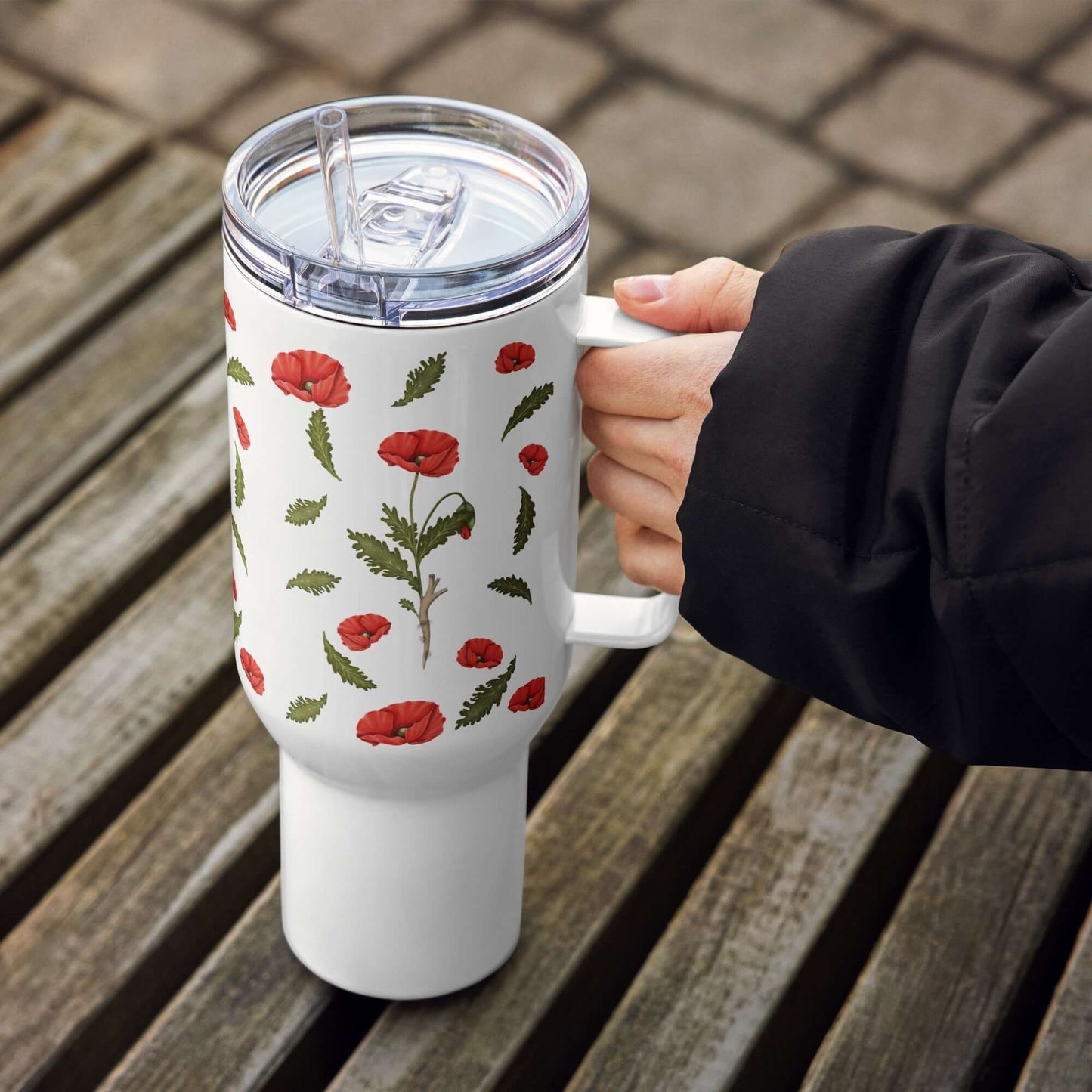 Poppy Design insulated tumbler held in hand on wooden surface, ideal for hot and cold beverages.