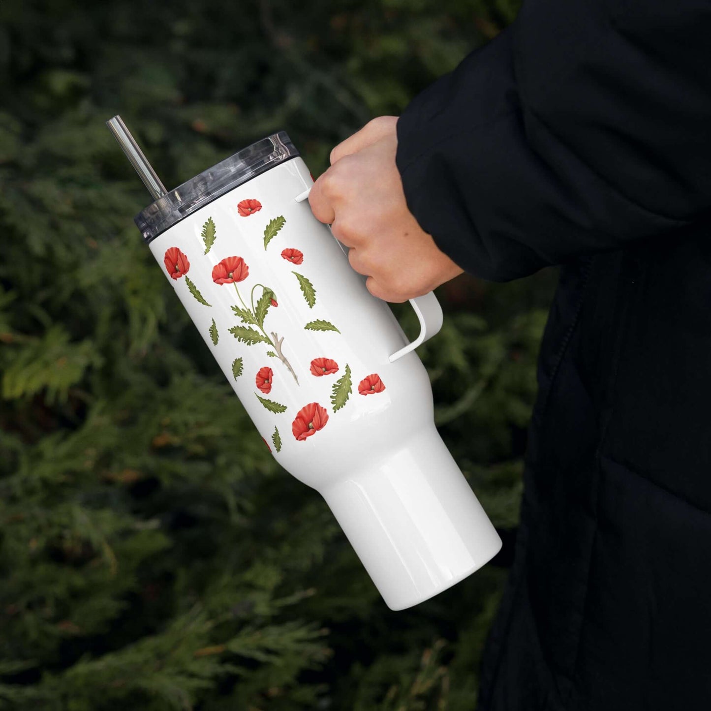 Insulated Poppy Design Tumbler with handle, ideal for hot and cold beverages, held against a natural backdrop.