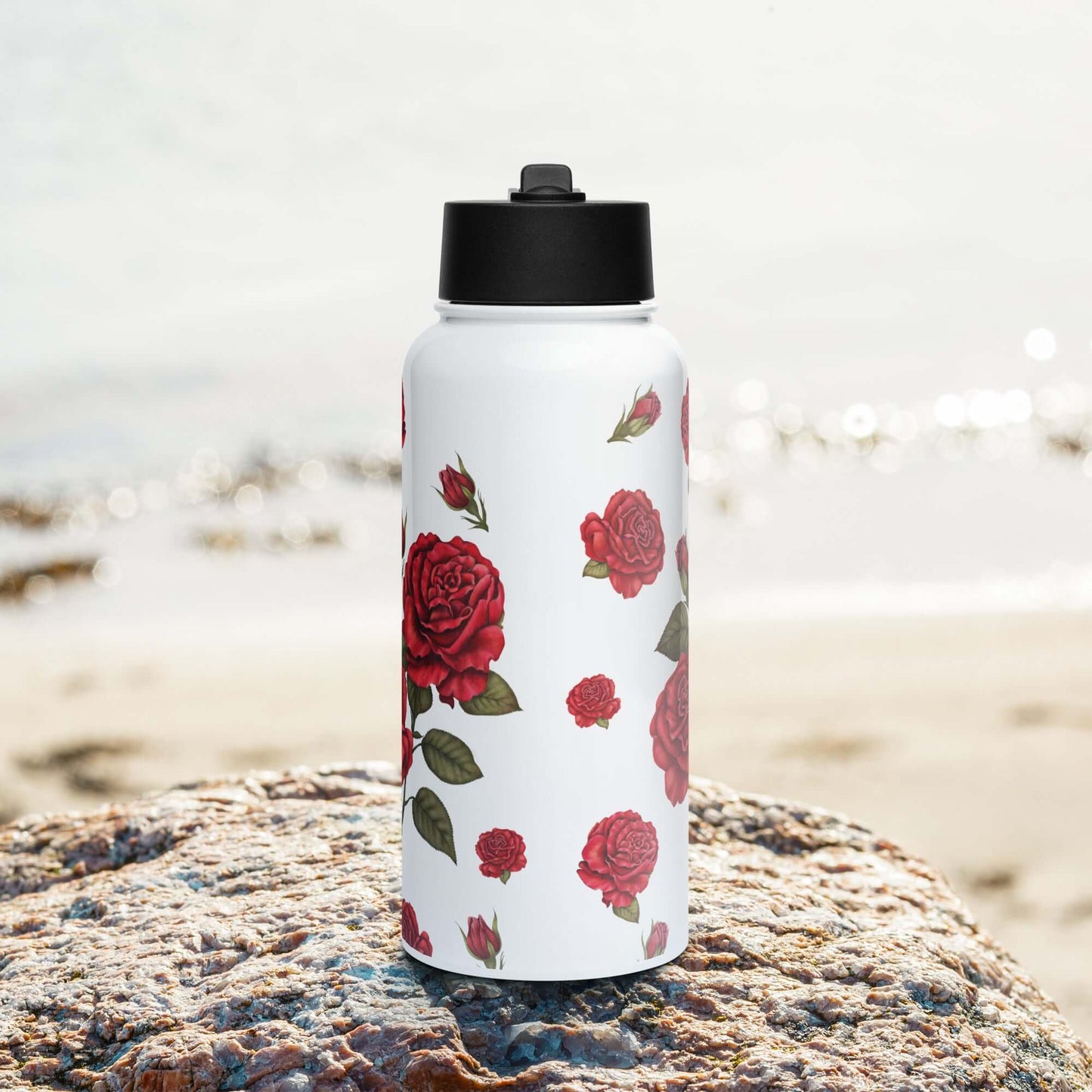 A front view of a rose water bottle with the ocean horizon in the background captures the soft, natural beauty of the romantic red rose design.