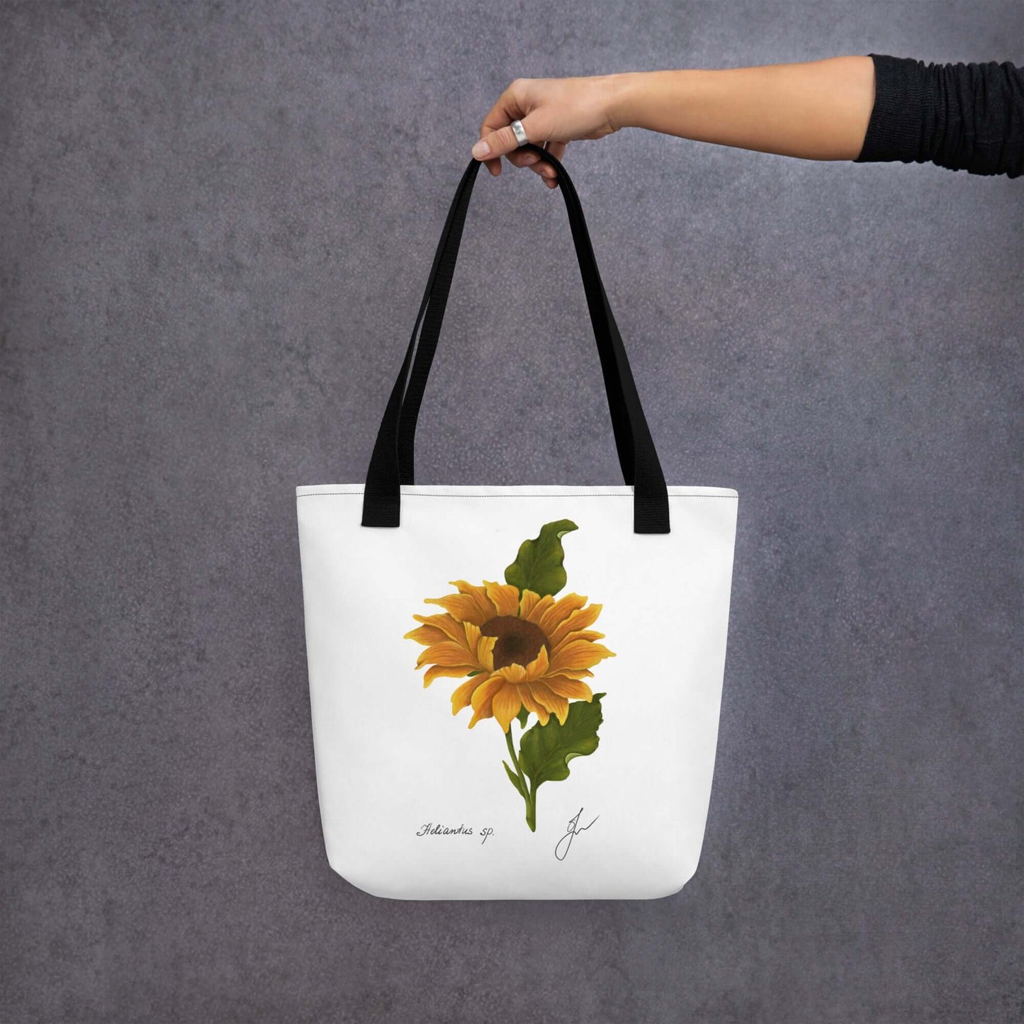 Hand holding a large sunflower botanical tote bag against a gray background, perfect gift for book lovers.