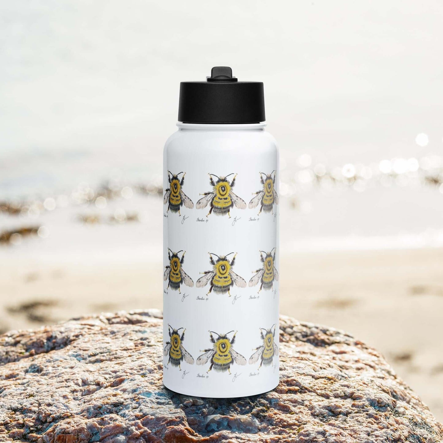 Front view on the beach: Vibrant Bumblebee water bottle with straw lid, adding a pop of color to your beach day.