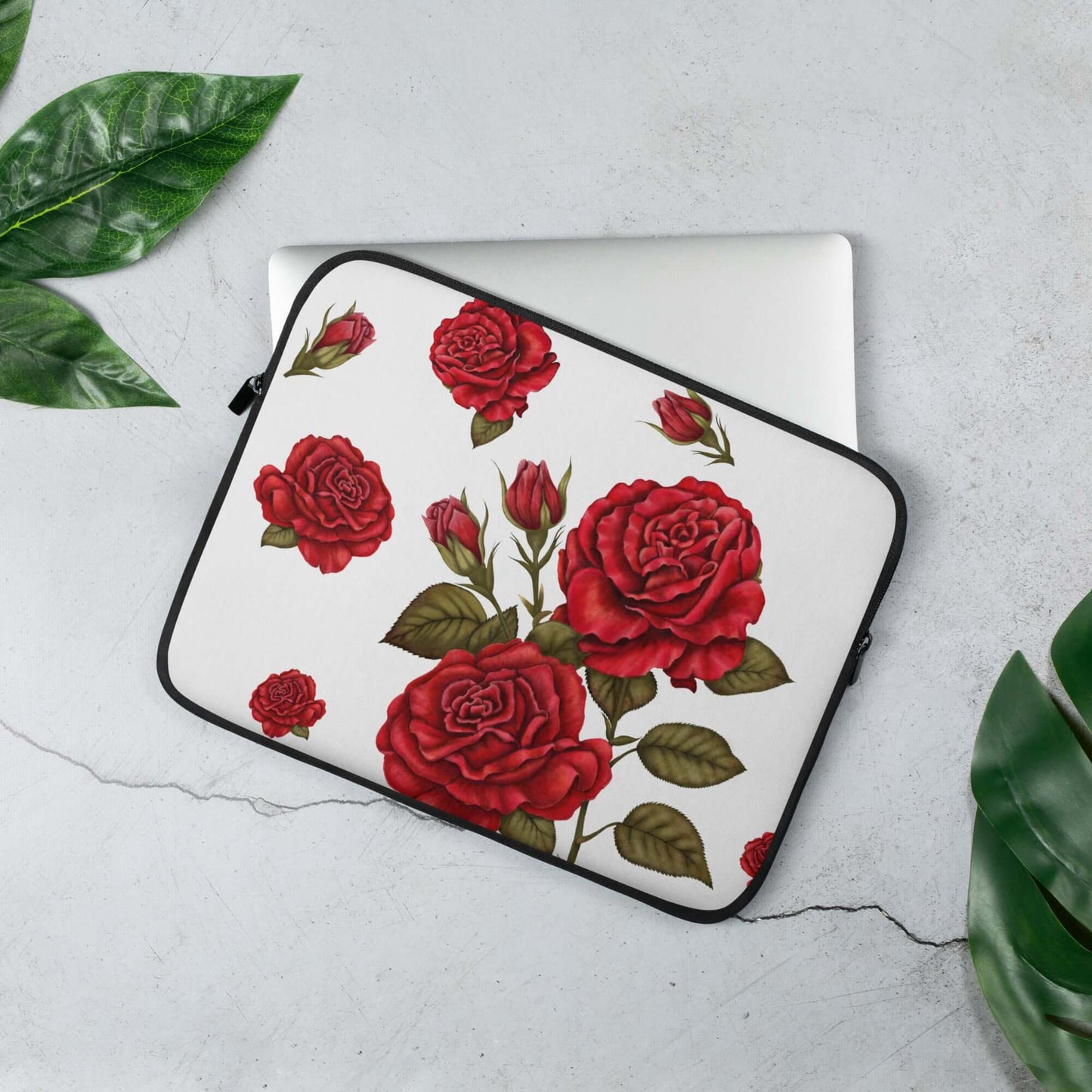 13'' red rose design laptop sleeves with open zip and laptop slightly extracted, next to few green leaves and grey background