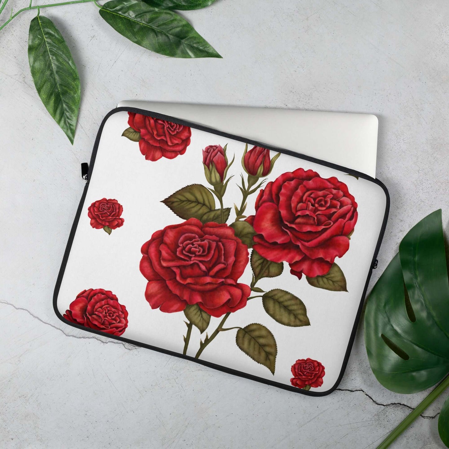 15'' red rose design laptop sleeves with open zip and laptop slightly extracted, next to few green leaves and grey background