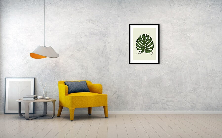 monstera-fine art print with black frame hanging on a wall next to a yellow sofa and a lamp